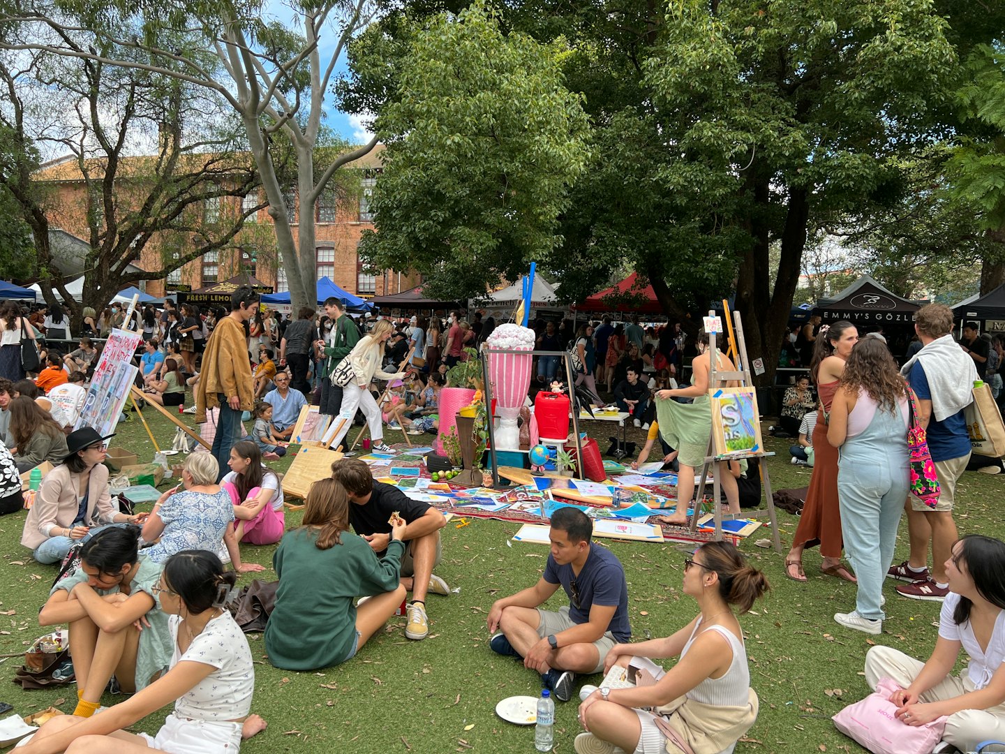 People enjoy an outdoor art fair in a park.